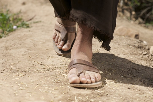 man's feet in sandals walking on dusty road in the antiquity, Holy Land, times of Jesus